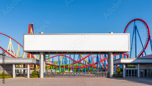 A large blank horizontal billboard stands at the entrance to an amusement park with a roller coaster in the background. The empty space is a perfect mockup for park promotions, event schedules, or tic