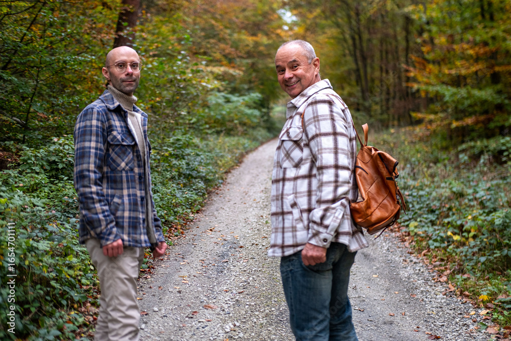 Fototapeta premium Two men walking together, Happy Mature friends walking together, Older father and young adult son, autumn walk, casual talk, active aging, adult relationship, warm bond, family connection