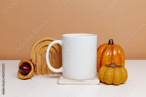Ceramic mockup white cup on wooden coaster with pumpkin and autumn decorations. Mockup mug for design, logo or print, autumn, Thanksgiving theme