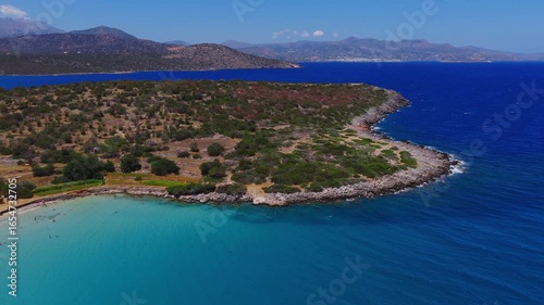 Wallpaper Mural Aerial view of Voulisma Beach in Crete, showing rocky coastline, deep blue waters with ripples, and distant hills with slow sweeping camera motion. Torontodigital.ca