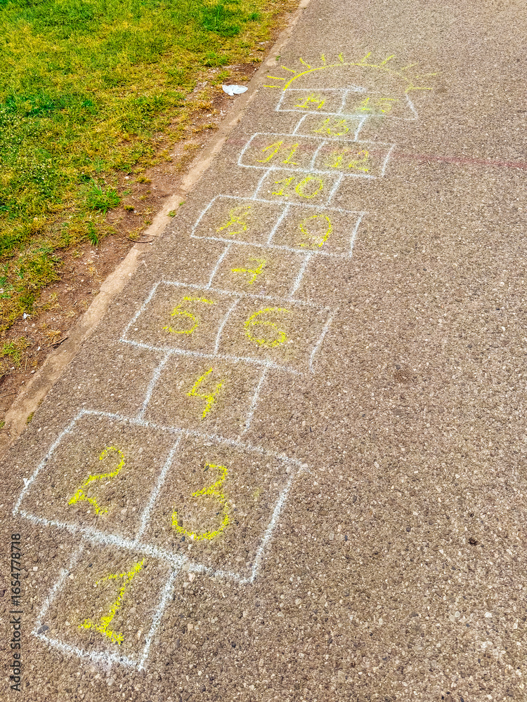 Obraz premium A hopscotch game drawn with chalk on the pavement in the park. Childhood, nostalgia and playful leisure activity connecting imagination with movement and joy.