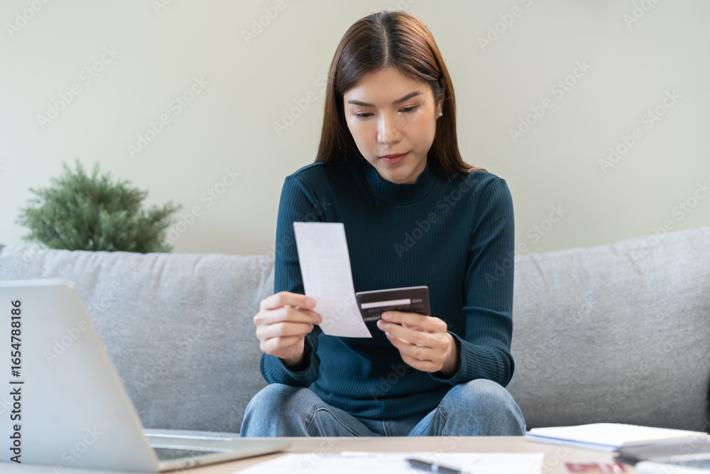 Stressed asian young business woman, employee calculate expenses of monthly, hand holding bills, receipt and credit card to payment on table at home. Financial, finance of banking concept. Stressed asian young business woman, employee calculate expenses of monthly, hand holding bills, receipt and credit card to payment on table at home. Financial, finance of banking concept.