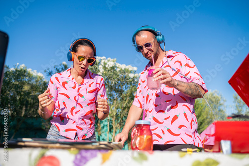 DJs playing music at summer party, enjoying cocktail and having fun