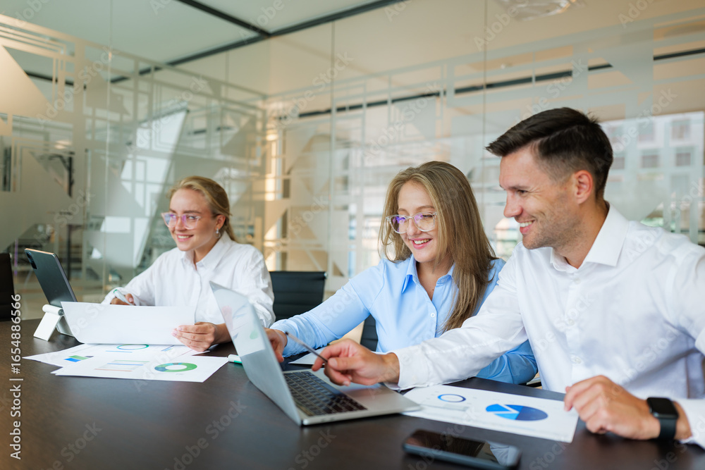 Fototapeta premium Collaborative teamwork in a modern office as professionals analyze data and prepare reports