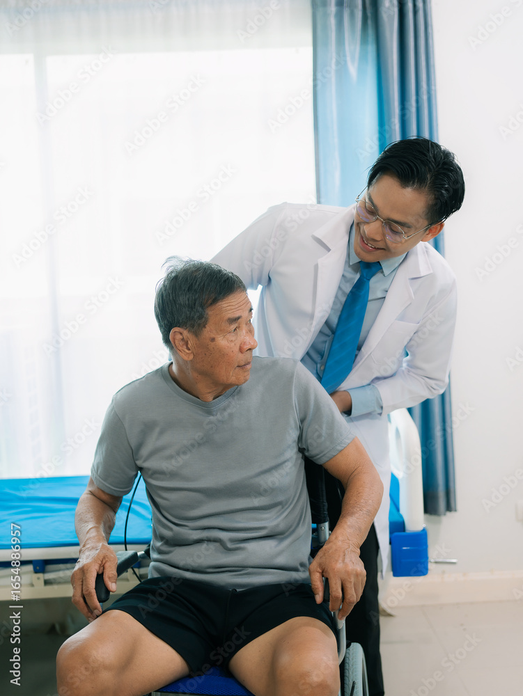 Fototapeta premium A skilled male physical therapist examines an elderly male patient lying on a bed, checking his muscle strength in a hospital examination room.