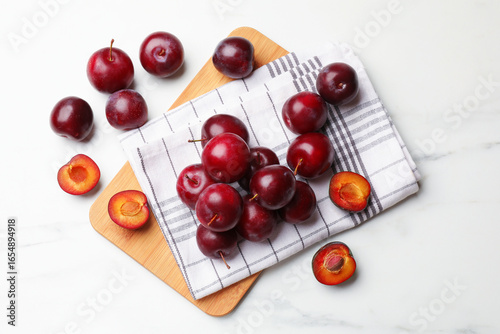 Billede på lærred Ripe cherry plums on white marble table, flat lay