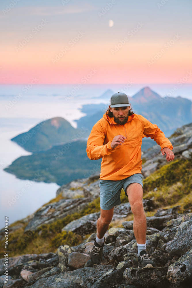 Fototapeta premium Man athlete trail running in sunset mountains travel in Norway active adventure vacations, male traveler hiking solo healthy lifestyle extreme trip fitness endurance motivation