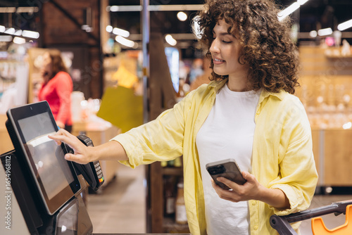 Customer using self checkout kiosk in supermarket