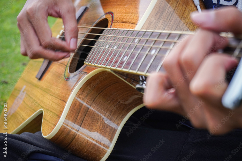 Fototapeta premium Man's hand is plucking the guitar strings. Man playing guitar.