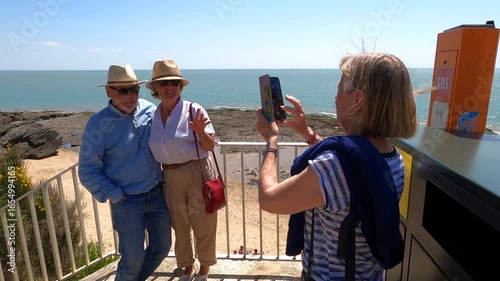Woman taking pictures of a couple as the husband playfully jokes around
