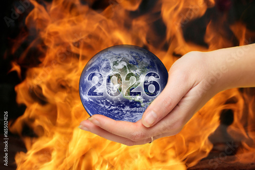 a hand holding the Earth, which is covered in flame and fire. The photo, a powerful symbol of a global disaster, is perfect for a theme of climate change or a modern challenge in the year 2026