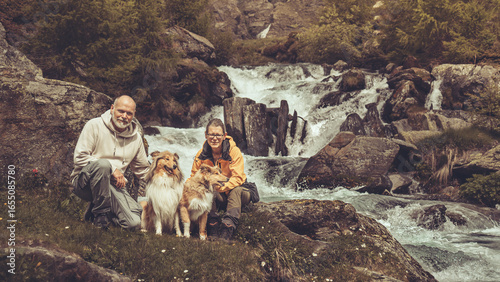 Mann und Frau sitzen mit 2 rough Collies im Urlaub am Wasserfall, Wildbach in S√ºdtirol Texelgruppe Berge