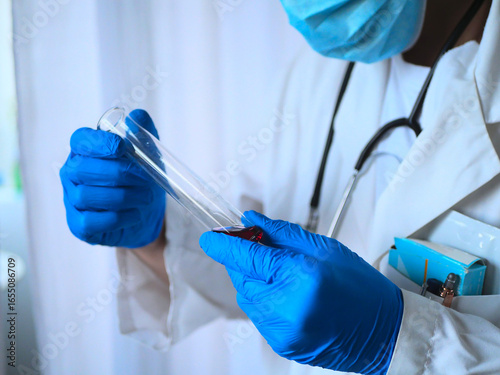 фотографія Médecin en blouse blanche tenant un tube à essai rempli de liquide rouge en labo
