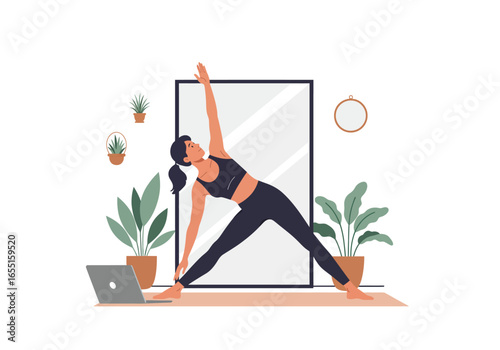 A woman practices yoga indoors, demonstrating a triangle pose with a laptop nearby.