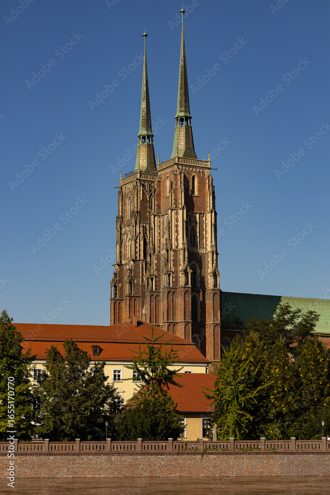 Naklejka premium Majestic gothic cathedral with twin spires under clear blue sky, symbol of Catholic faith, education, enlightenment and spiritual heritage. Religion, history, culture and Christian values