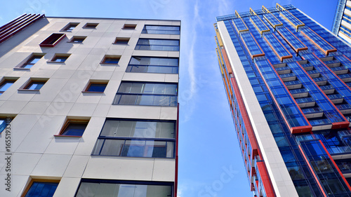 Exterior of a high modern multi-story apartment building - facade, windows and balconies. Timeless glass facade. Modern urban living district.