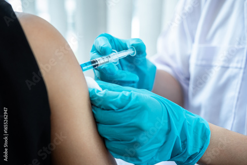 Doctor making a vaccination into patient with needle getting immune vaccine at arm for flu shot, coronavirus protective of epidemic