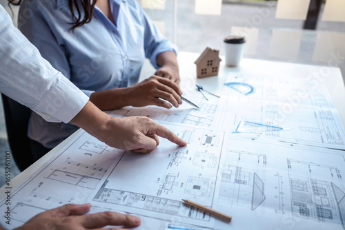 Architects or engineering team consulting and analyzing working on objects tools and construction drawings inspection planning new architectural project on blueprint and model house in modern office