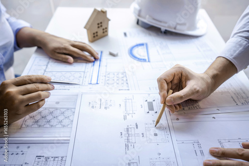 Architects or engineering team consulting and analyzing working on objects tools and construction drawings inspection planning new architectural project on blueprint and model house in modern office