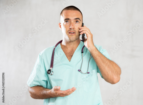 Foto Engaged in direct telephonic conversation, male physician imparts medical insights remotely