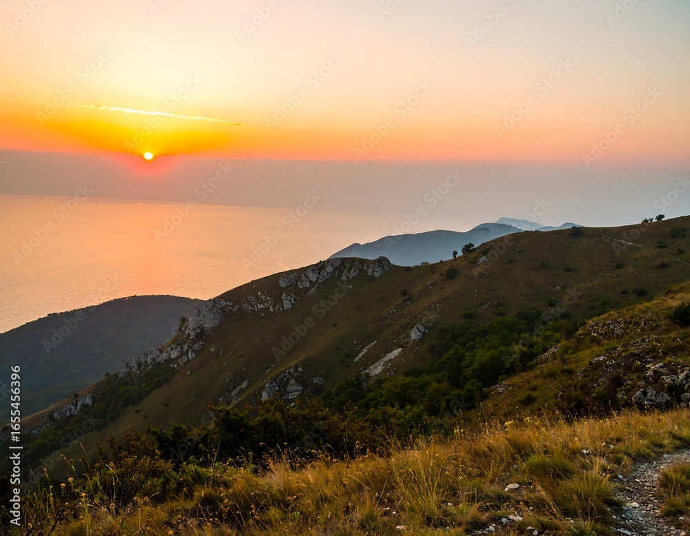 Obraz premium Sunrise over a mountain range overlooking a body of water