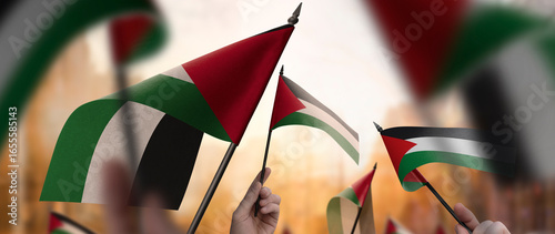 Palestine flags in their hands on a blurred urban background