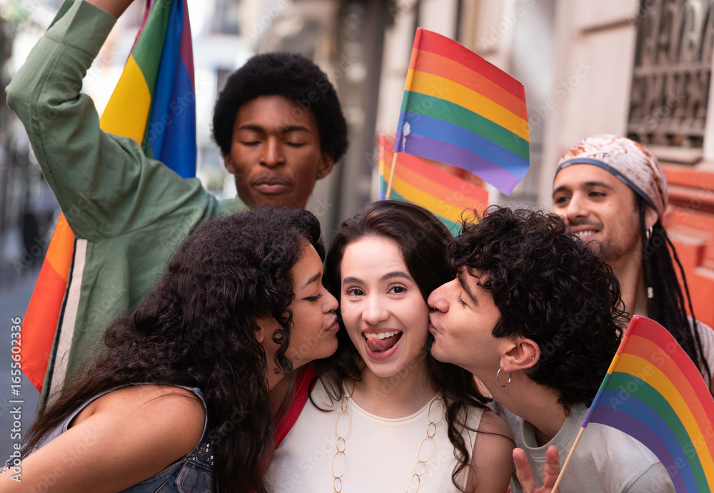 Fototapeta premium Portrait of a group of young lgbt people celebrating at a pride parade, kissing , showing love and holding rainbow flags