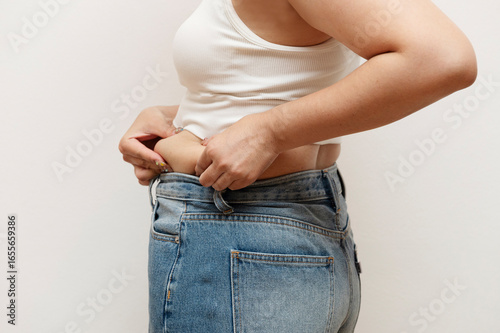 Woman pinching side belly fat in jeans
