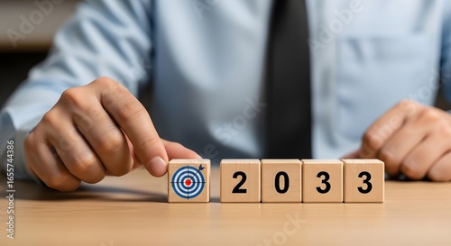 A person placing a target block next to blocks spelling out the year twenty thirty three on a table