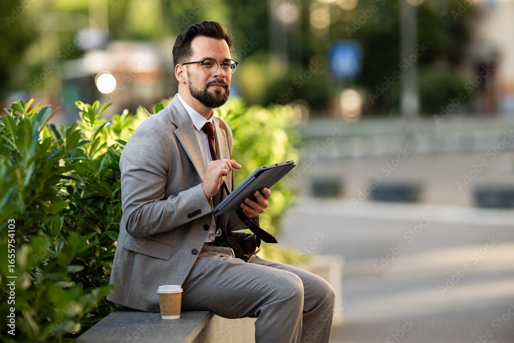 Obraz premium Businessman using digital tablet while sitting outdoors with coffee