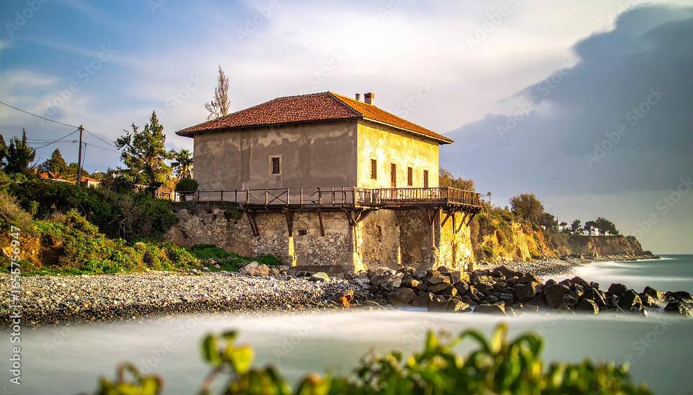 Obraz premium Rustic Cliffside House in Golden Light Over a Silky Long-Exposure Seascape