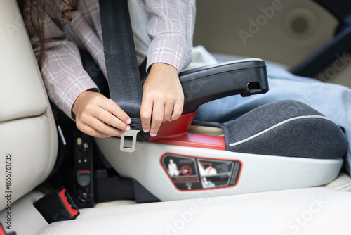 Close up picture of a kid sitting in a car with the seatbelt fixed