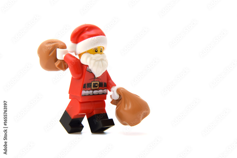 Naklejka premium Editorial illustrative image of lego minifigure of Santa Claus is walking with bags isolated on white.