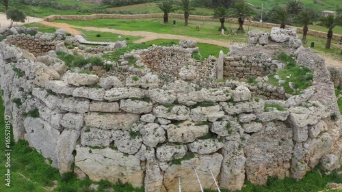 Drone shot of Ggantija Archaeological Park in Gozo with ancient stone temple ruins on green land
