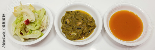 Cabbage salad, green curry with mushroom, and orange soup in white bowls on white background