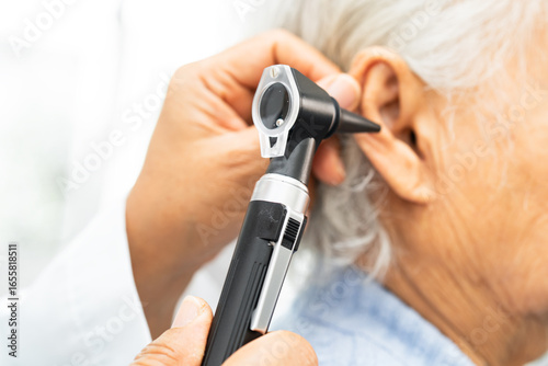 Tableau sur toile Audiologist or ENT doctor use otoscope checking ear of asian senior woman patient treating hearing loss problem