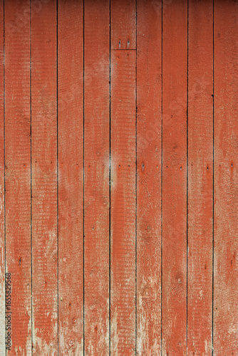 Textured red wooden wall displays wear and natural patterns, reflecting years of use in a quiet countryside environment.