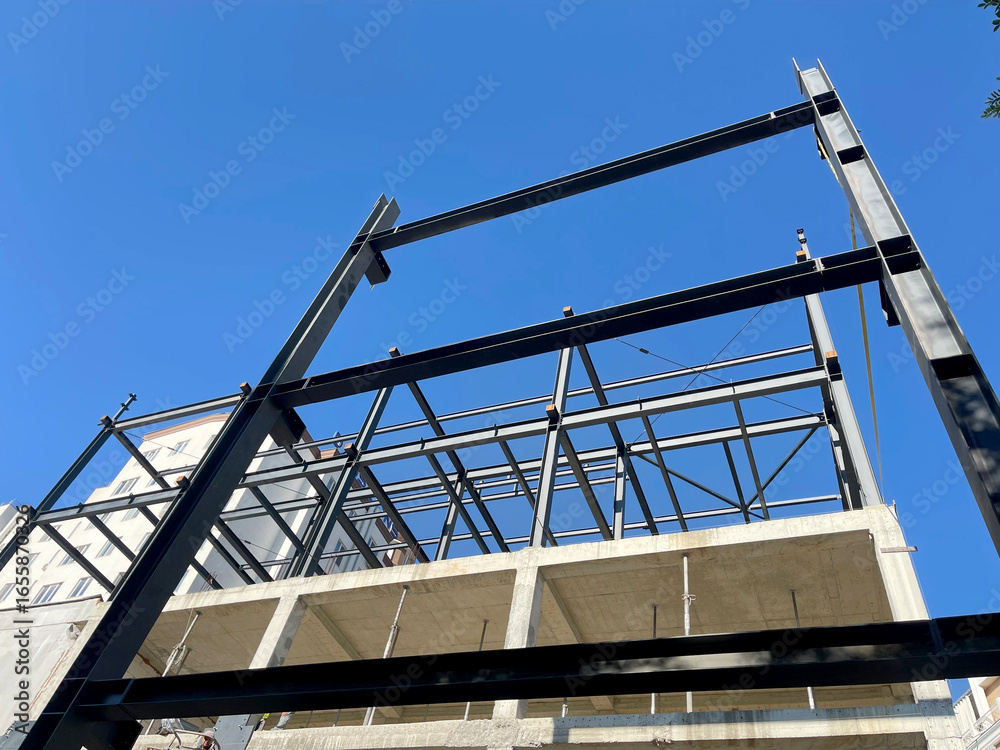 Steel frame structure of modern building under construction against blue sky - useful for architecture, engineering, construction industry, urban development, and structural design visuals Steel frame structure of modern building under construction against blue sky - useful for architecture, engineering, construction industry, urban development, and structural design visuals