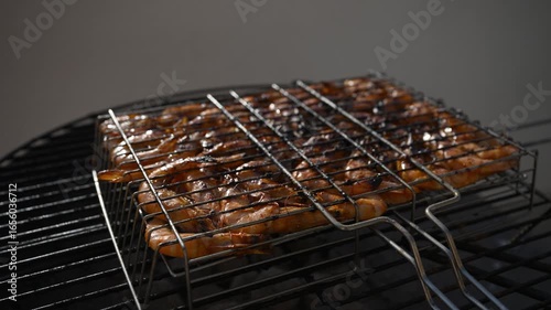 Succulent jumbo shrimps sizzling in metal basket, carefully grilling over hot charcoal with golden-brown edges developing against neutral gray background