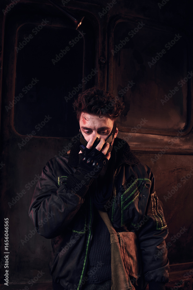 Obraz premium A young man stands in a grim environment, showing resilience and determination amidst chaos.