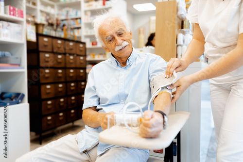 Fotografia Female pharmacist checking an elderly man blood pressure in a pharmacy