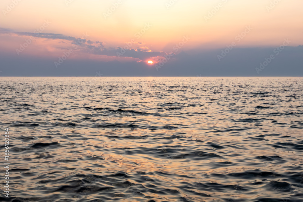 Fototapeta premium calm sea horizon under sunset sky. minimal composition with warm sky gradient under calm sea surface with gentle waves. nature