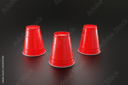 Three upside down red disposable plastic cups on a black background. Illustration of the concept of guessing, betting, unknown and games