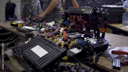 Technician repairing car electronic control units with wiring and connectors on workbench. Concept of diagnostics, automotive service and electronic system maintenance