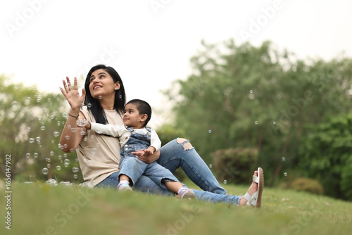 Mother And Child Play With Bubbles In The Park