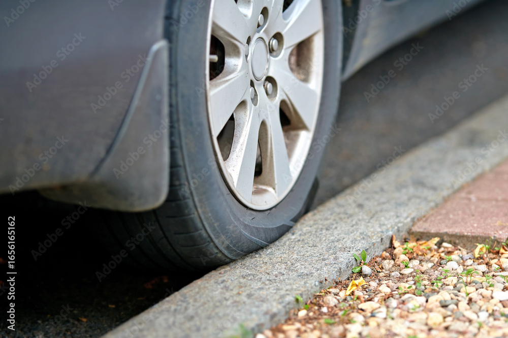 Φωτογραφία Vehicle tire making direct contact with curb edge during rainy weather, road hazard, improper parking, and potential automotive maintenance problems, risk of sidewall damage