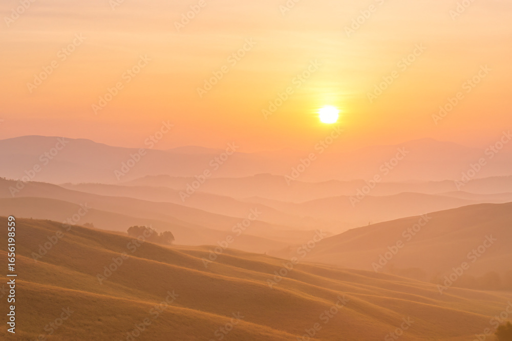 Obraz premium Peaceful Sunrise Landscape with Rolling Hills in Yellow and Pink Light
