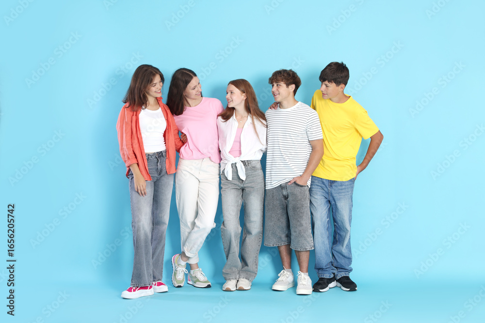 Obraz premium Full-length portrait of happy teenage friends on light blue background