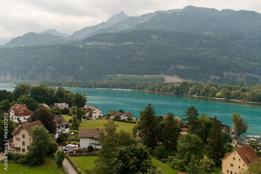 Fototapeta premium View of Lake Walen, Switzerland, Swiss Alps, Canton St. Gallen, Chatzenberg, summer 2025. Trees, meadows and small villages in the valley. mountains, beautiful landscape hiking, recreation.