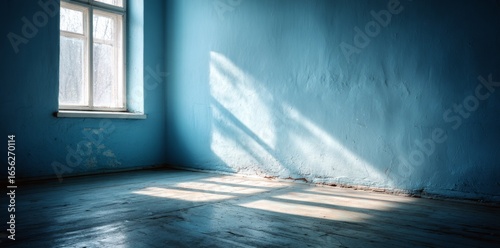 A deep blue paint job and a large window that brings in natural light combine to create playful shadows on the wall in the room